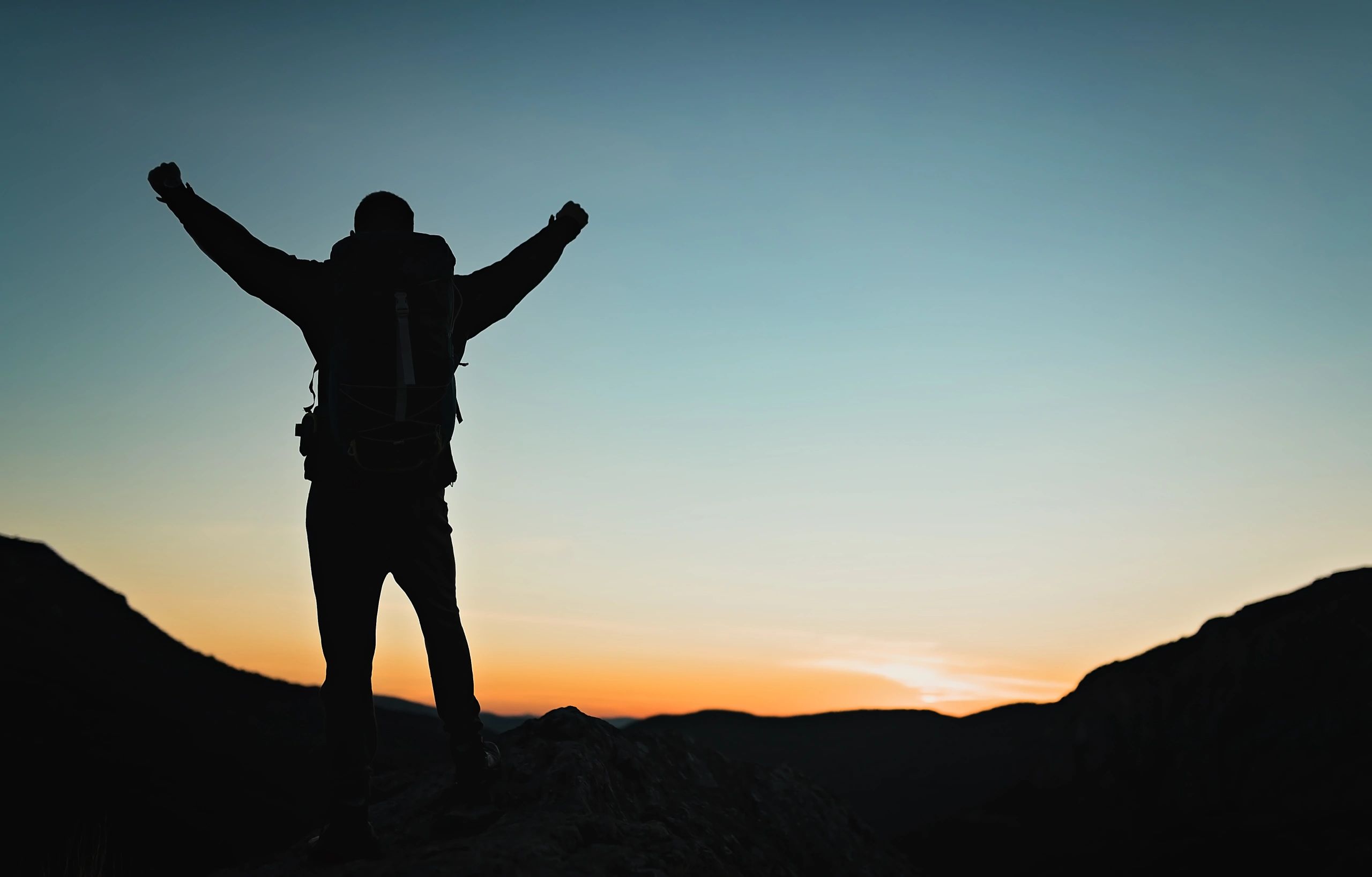 Silhouette with raised arms in worship at dusk
